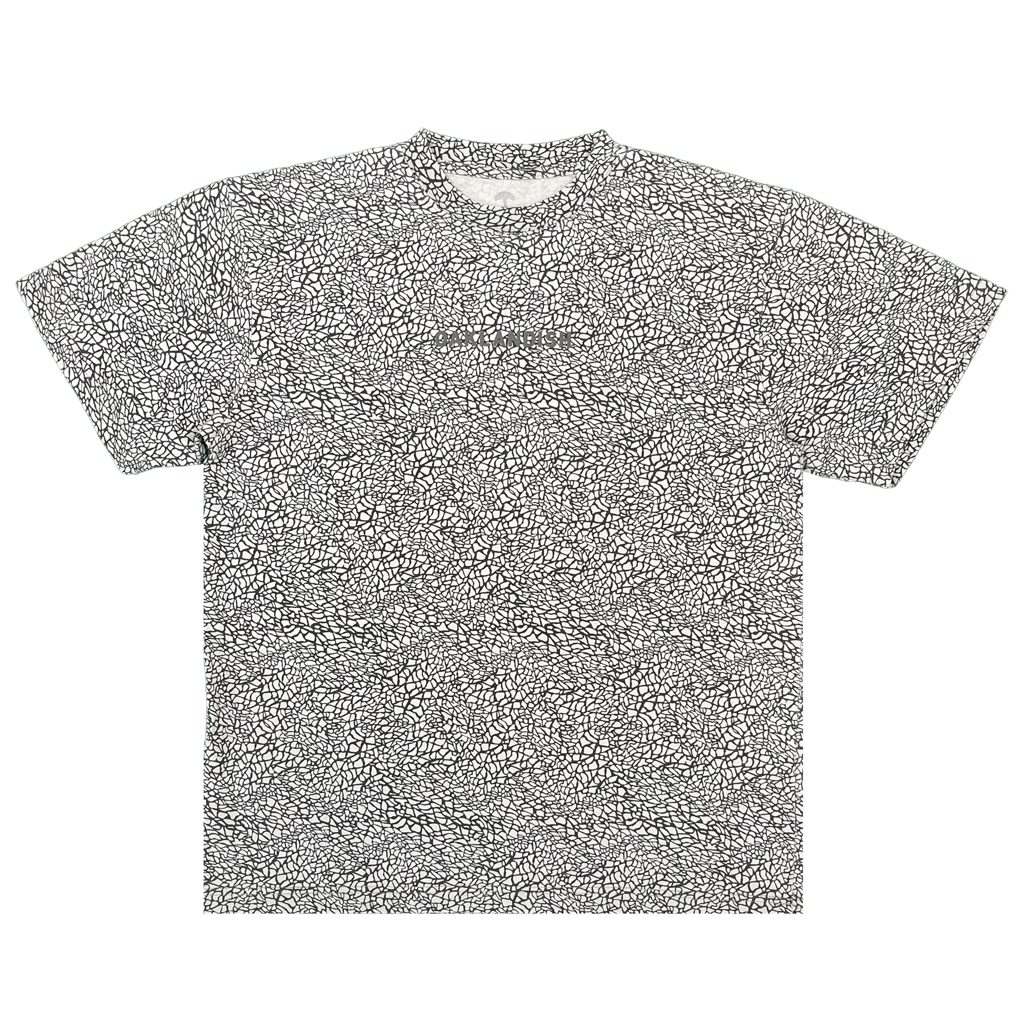 Short-sleeved Oaklandish Classic Logo Tee in a classic fit, crafted from heavyweight cotton and featuring an all-over black-and-white cracked elephant print pattern. The shirt is laid flat on a white background and showcases a subtle puff print Oaklandish logo at the center of the chest. Finished with a ribbed collar, straight hem, and no visible tags.