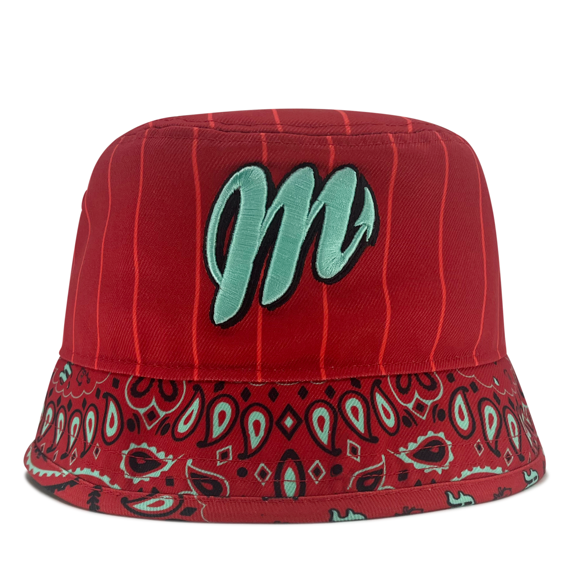 The New Era Diablos Paisley Bucket from Retail Vendors is a red bucket hat featuring a teal embroidered letter "M" on the front. It is crafted from high-quality polyester and boasts vertical pinstripes on the upper part, with a paisley bandana pattern on the brim. The underside of the brim also showcases the same red, teal, and black paisley design.