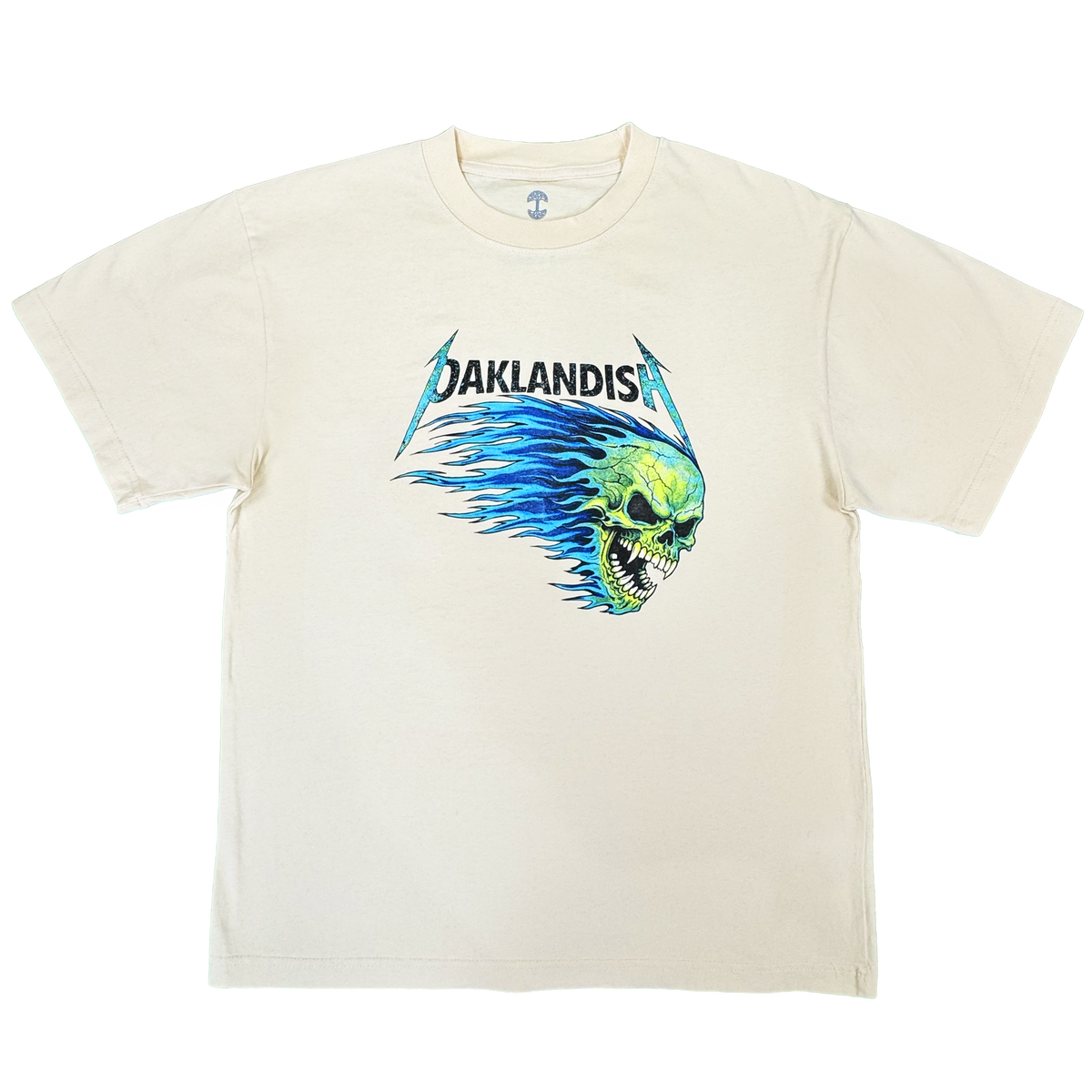 Introducing the Sandman Tee by Oaklandish: a men’s cotton t-shirt in cream, featuring “OAKLANDISH” in black, stylized lettering above a bold green flaming skull graphic with blue flames extending behind it, all centered on the chest. This classic fit tee comes with short sleeves and a simple crew neckline.