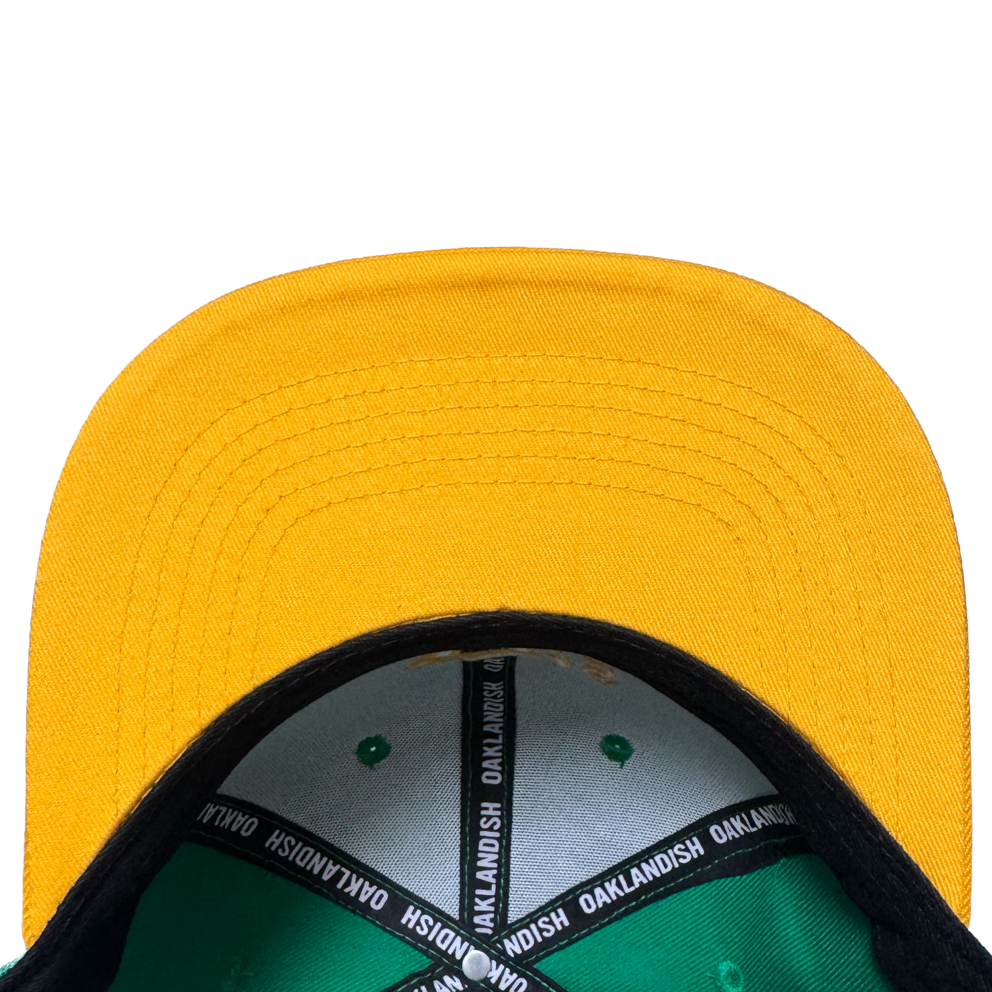 A close-up, top-down view of the Oakland Ballers Snapback by Oakland Ballers features a yellow cap with green interior, black brim underside, and an "OAKLANDISH" inner band, echoing Oakland baseball style on a white background.