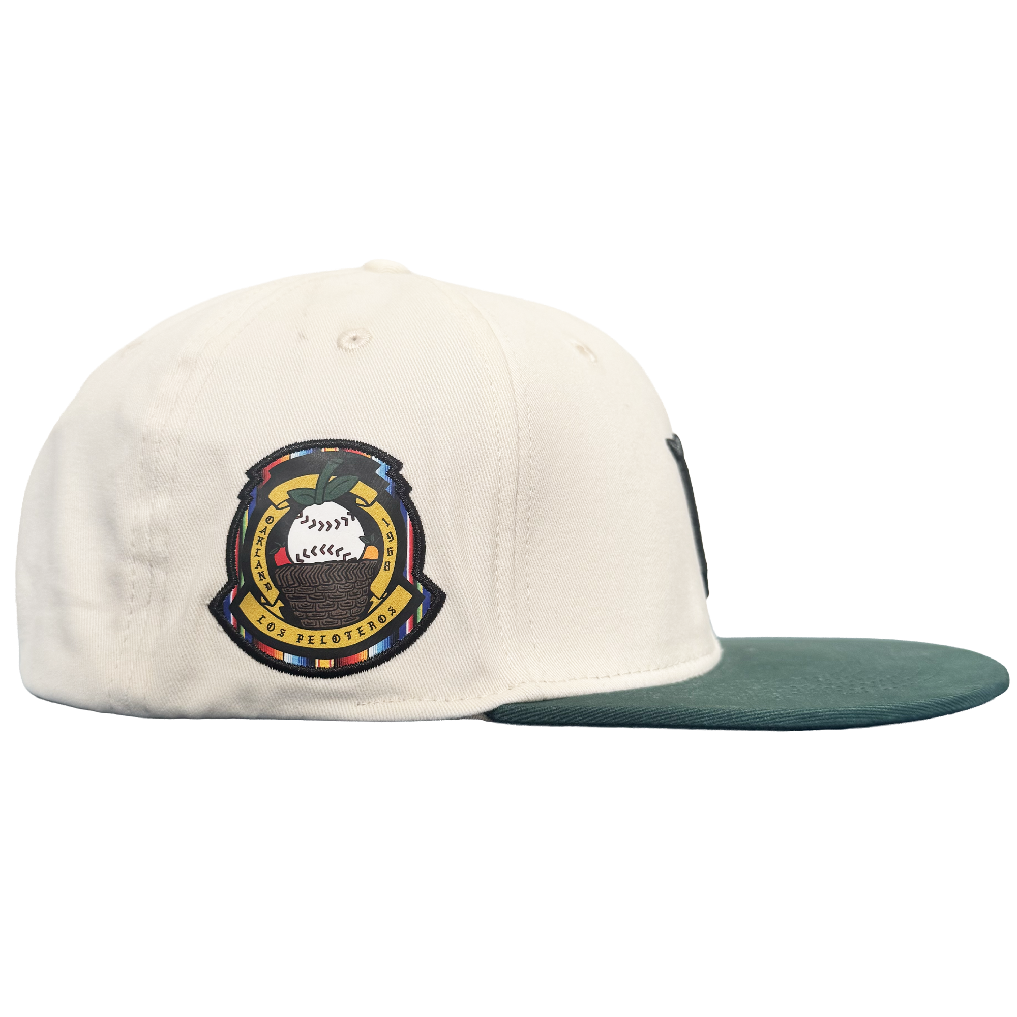 A white Oakland Peloteros Hat by the Oakland Ballers is displayed from a side view. The hat features a green brim and a colorful embroidered patch with a stylized baseball, crossed bats, and intricate detailing—a tribute to the team as an exciting addition to the Pioneer League. The plain white background emphasizes the vibrant colors and design of the cap.