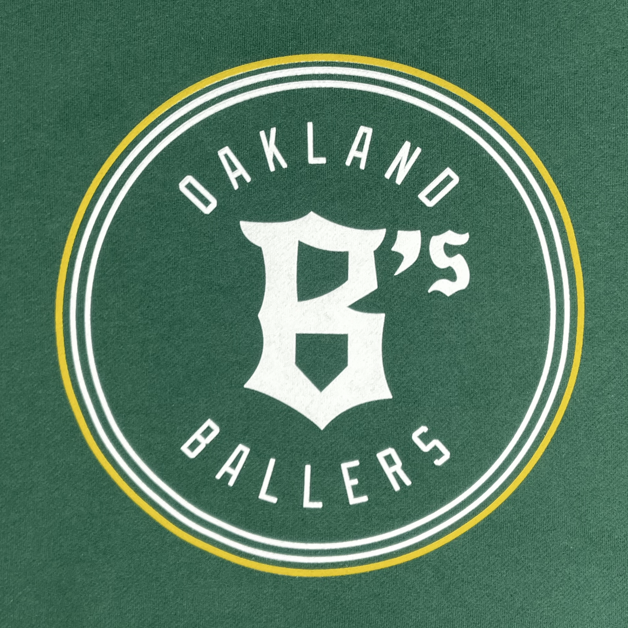 Showcase your Oakland Ballers pride with the Oakland Ballers Logo Heavyweight Hoodie by Oakland Ballers. Features a bold circular green logo with large white stylized "B’s" at the center, gold and white outlines, and “OAKLAND” above, “BALLERS” below in arched uppercase text.
