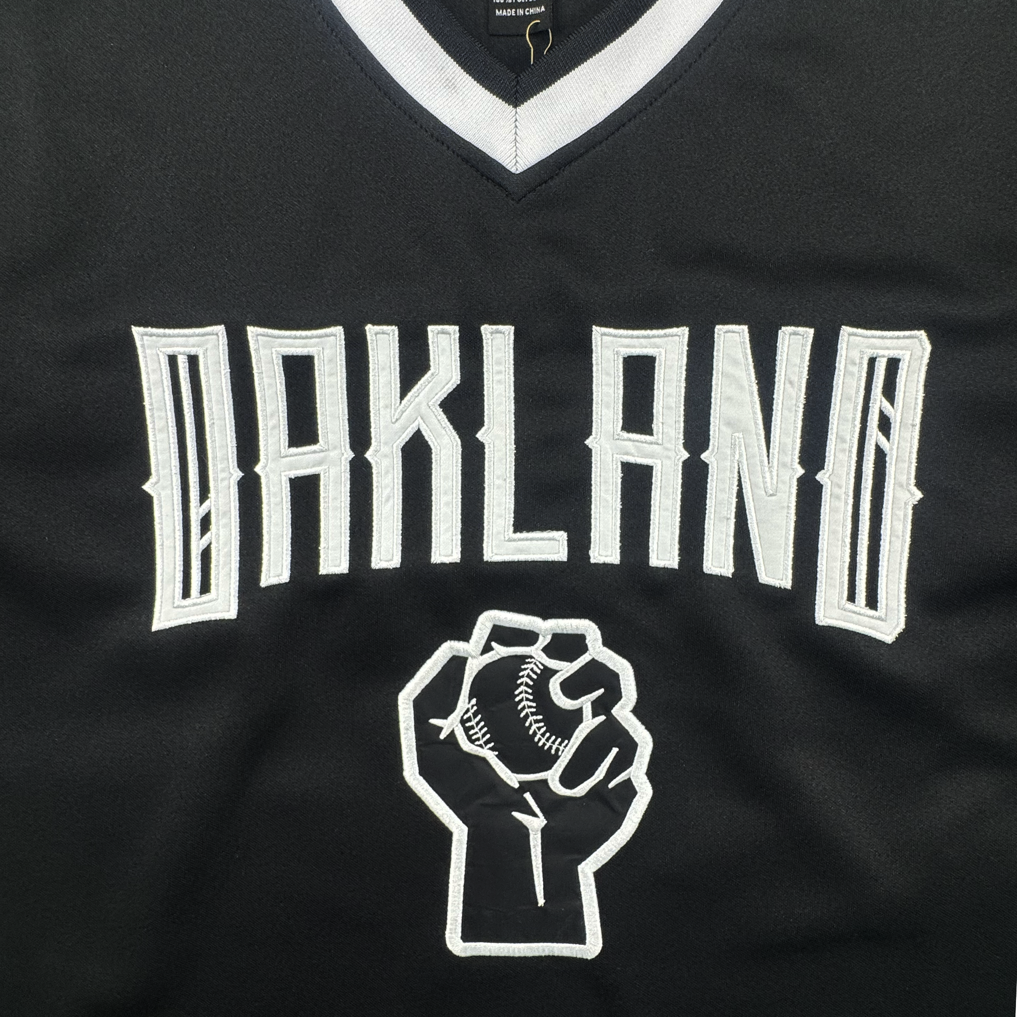 The Oakland Ballers Stands Up Jersey features “OAKLAND” in bold white letters on black, with a raised fist holding a baseball below—symbolizing strength and solidarity for this pioneering team.