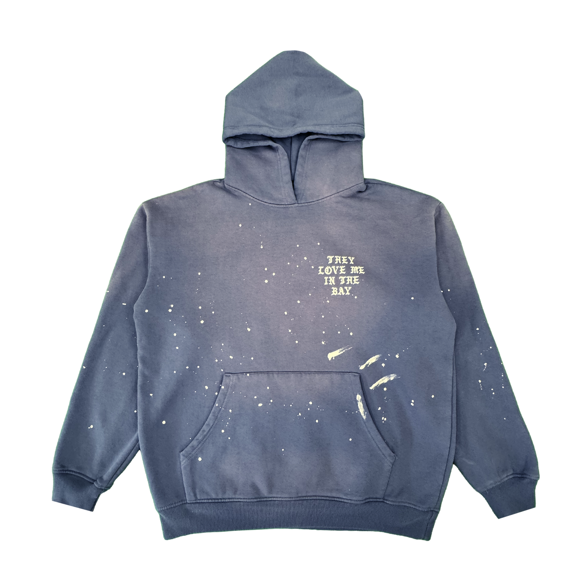 Introducing the They Love Me Hoodie By Doc from By DOC—a vintage-inspired blue men’s pullover hoodie accented with distinctive white paint splatters and a practical front pocket. Crafted from heavyweight fleece, this relaxed-fit hoodie sports a drawstring-free hood for effortless comfort. The left chest features “THEY LOVE ME IN THE BAY.” printed in white, adding a unique touch to its laid-back style.