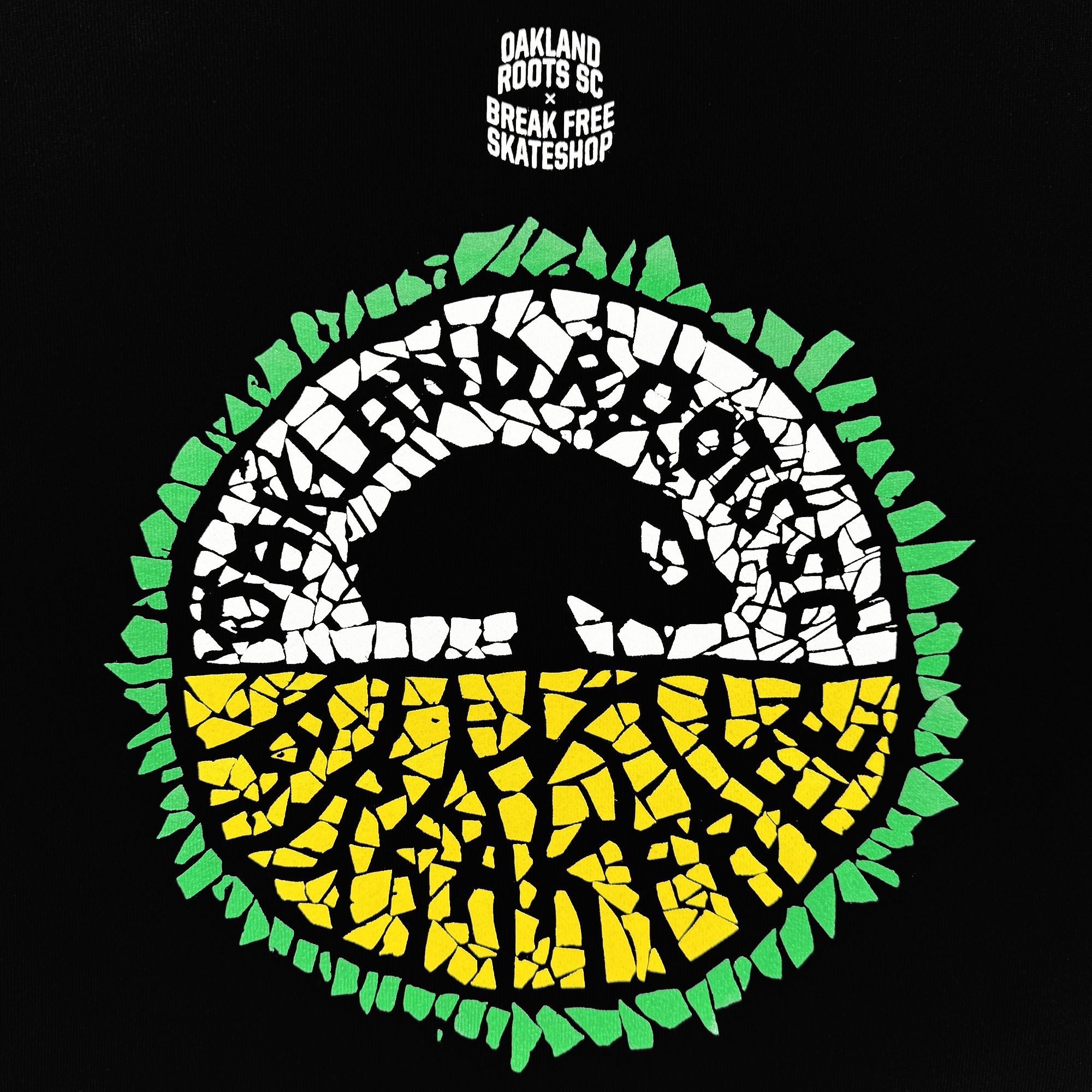 The Oakland Roots SC X Break Free Hoodie by Oakland Roots SC features a mosaic logo with a black bear silhouette, "OAKLAND ROOTS" above yellow and green roots, and “OAKLAND ROOTS SC x BREAK FREE SKATESHOP” in small white text on black.