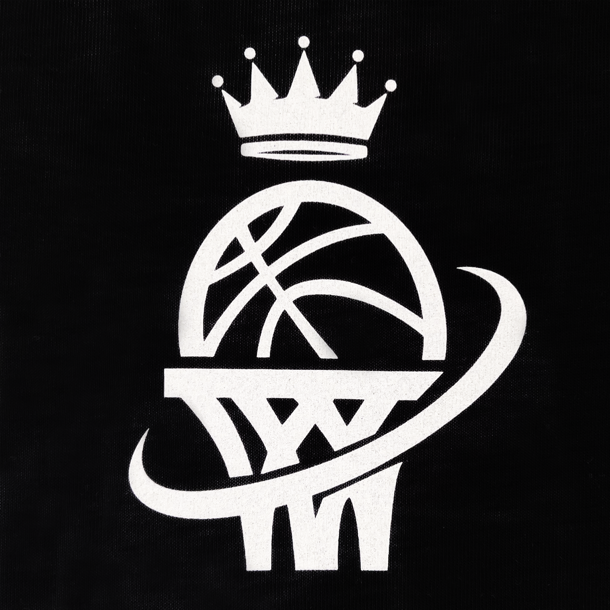 The WPBA Core LS Tee by Oaklandish showcases a stylized white basketball on a black background, featuring a basketball resting on a hoop with a swoosh wrapping around both. A simple five-pointed crown above the ball signifies grandeur or royalty, evoking empowerment in women's sports.